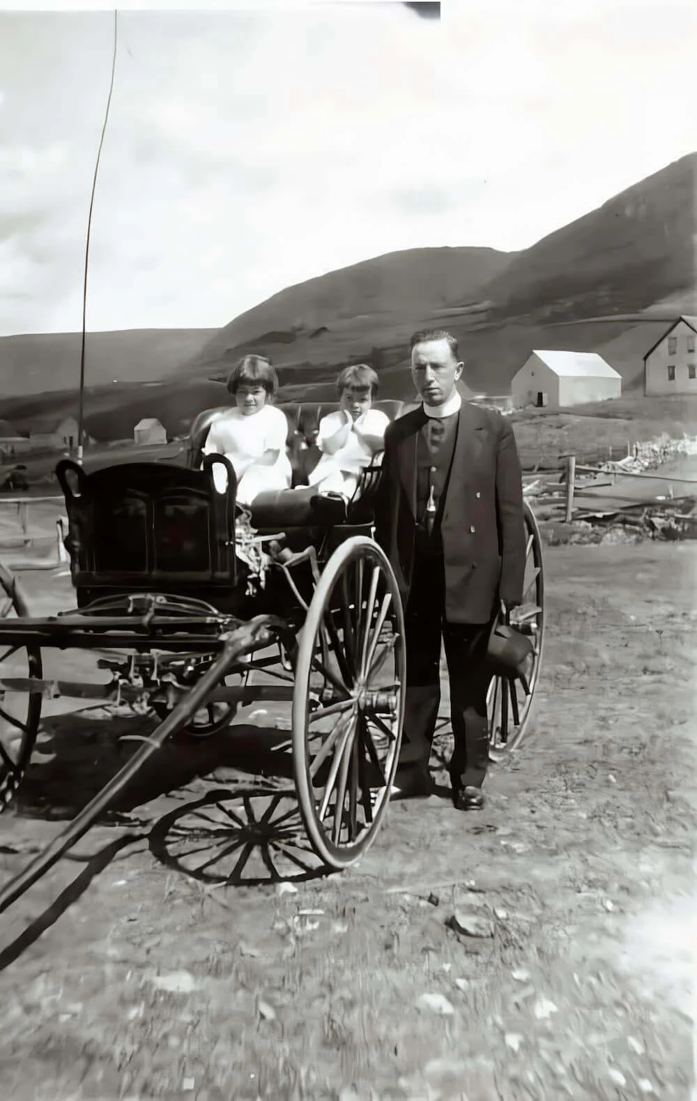 Father Denis Doucet with two children beside a car in Bersimis
